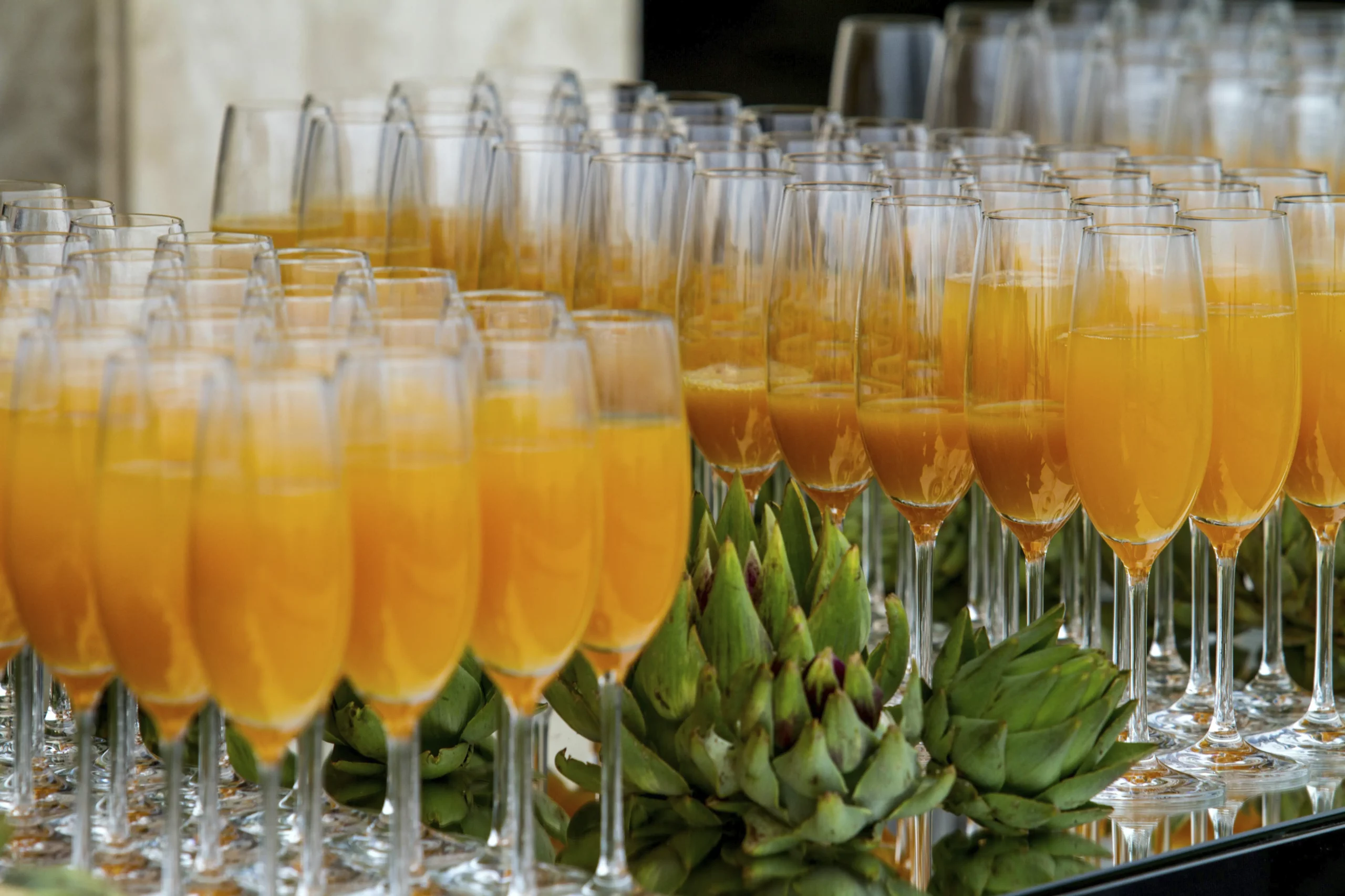 Cocktails frais pour vos événements Rangée de flûtes remplies d’un cocktail orange sur table de réception