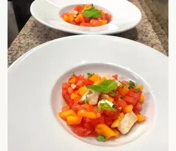 Duo de salades fraîches à base de tomates, pastèque, pêche et mozzarella, décorées de basilic Duo de salades fraîches à base de tomates, pastèque, pêche et mozzarella, décorées de basilic