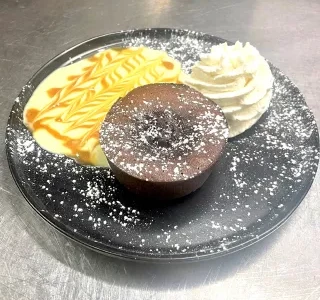 Fondant au chocolat avec cœur coulant, accompagné de crème anglaise décorée au caramel et d'une rosace de chantilly Fondant au chocolat avec cœur coulant, accompagné de crème anglaise décorée au caramel et d'une rosace de chantilly