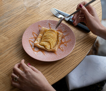 Tarte fine aux pommes servie tiède avec sauce caramel, vue du dessus avec des mains prêtes à déguster Tarte fine aux pommes servie tiède avec sauce caramel, vue du dessus avec des mains prêtes à déguster