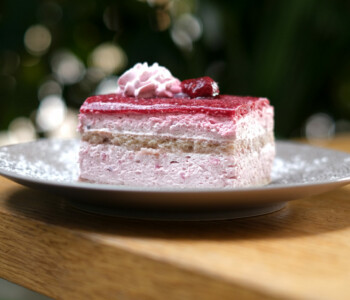 Part de gâteau à la mousse de framboise avec génoise, nappée d’un coulis et décorée de chantilly et framboise Part de gâteau à la mousse de framboise avec génoise, nappée d’un coulis et décorée de chantilly et framboise